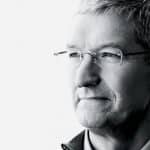 A grayscale photograph of a person with short, gray hair and glasses, looking off to the side. The individual appears thoughtful, wearing a collared shirt and a jacket. The plain white background enhances the profile, reminiscent of images from an educational event inspired by Apple’s minimalist style.