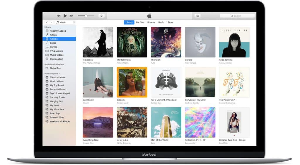 A MacBook displays the Apple Music app open on the Library tab, reminiscent of iTunes. Various album covers are visible, organized in a grid. The sidebar on the left shows options like Recently Added, Artists, Songs, Albums, and more. The top bar has controls for playback and navigation.