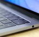 Close-up of a sleek, modern Mac keyboard and part of its screen. The focus is on the keys, with the power button particularly prominent. The laptop has a metallic finish and is placed on a light-colored surface. The screen displays a blue-toned background, emphasizing Apple’s signature design.