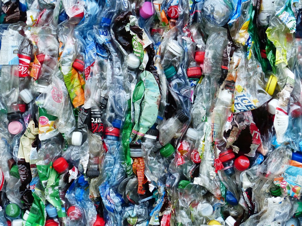 A close-up view of a compressed bale of various plastic waste materials including crushed bottles, wrappers, and caps of different colors and sizes. The chaotic yet intriguing pattern catches the eye, much like how scientists are captivated by a mutant enzyme that devours plastic.