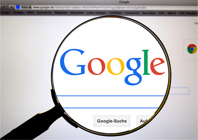 A magnifying glass focuses on the Google logo displayed on an iPhone screen. The search bar and 'Google-Suche' button are visible below, along with part of the Chrome browser window and tabs above, subtly emphasizing the blend of technology and privacy.