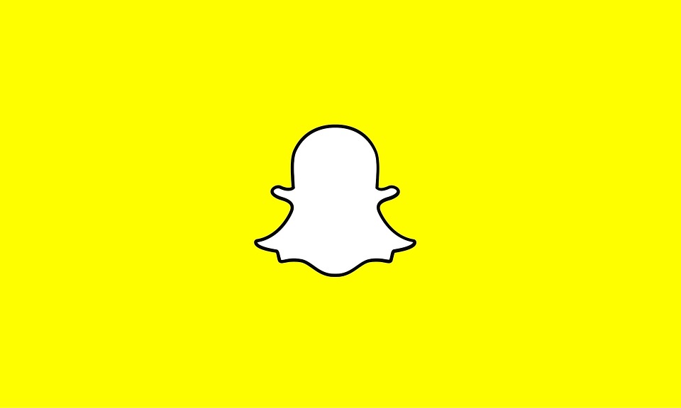 The image shows the redesigned Snapchat logo, featuring a white ghost with a thick black outline on a bright yellow background. The ghost appears to have arms outstretched. The background is entirely yellow with no other elements, representing Snapchat's bold leap on the brink of innovation.