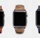 Three smartwatches with distinct leather bands are displayed side by side against a white background. The first has a brown leather band, the second features a textured light brown band reminiscent of summer Apple Watch bands, and the third boasts a blue leather band. All screens are black and turned off.