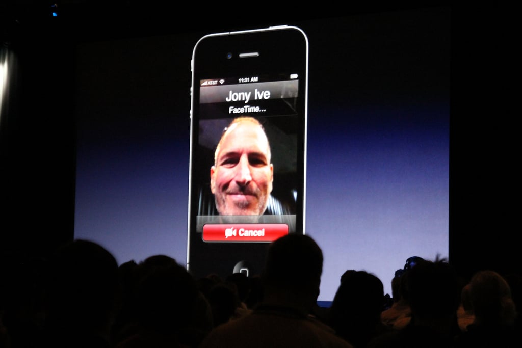 An audience watches a large screen displaying a smartphone with an exclusive FaceTime call in progress. The screen shows the contact name "Jony Ive," and a man's face is visible on the call. Below are options to "End" or "Mute" the call. The background fades to dark, highlighting Apple's ecosystem integration.