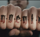 A close-up image of a person's knuckles with tattoos that spell out the word "ingenius" in a gothic font. The hand is clenched into fists, with the background blurred to emphasize the tattooed letters, reminiscent of a rebellious Samsung ad.