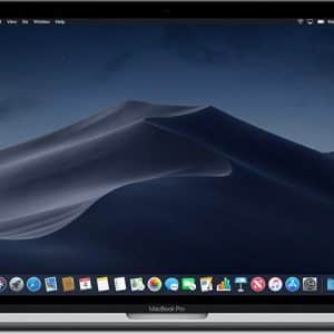 An open MacBook Pro displaying its home screen with a Mojave desert sand dune wallpaper. Various application icons such as Finder, Safari, Siri, and others are visible in the dock at the bottom of the screen. The menu bar at the top shows system menus as Apple launches MacOS Mojave.