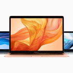 Three new MacBook Air laptops in different colors (Space Gray, Gold, and Silver) are displayed with their screens open. The front laptop shows an abstract orange design on the screen, while the other two have blue abstract designs. All laptops are set against a plain white background, drawing positive reviews.