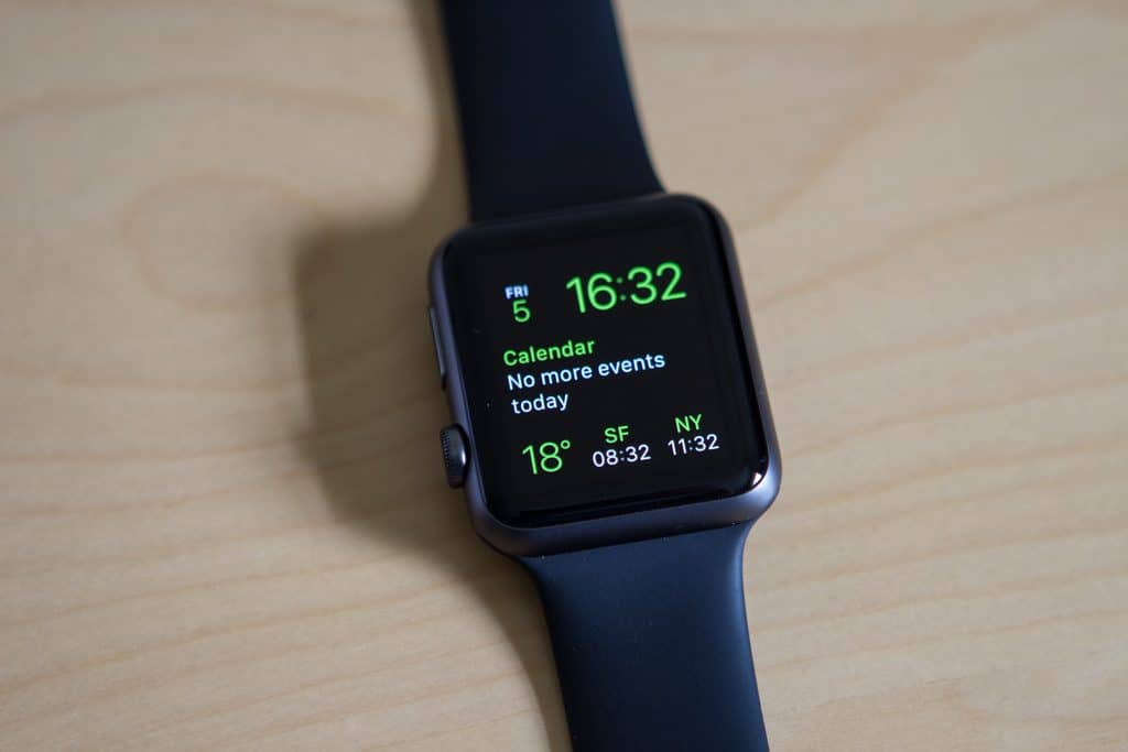 A sleek black Apple Watch displaying a calendar notification reads "No more events today." The time shown is 16:32, and it also features weather information at 18°C, along with times for SF at 08:32 and NY at 11:32. Opt into the replacement program for seamless repairs if needed.