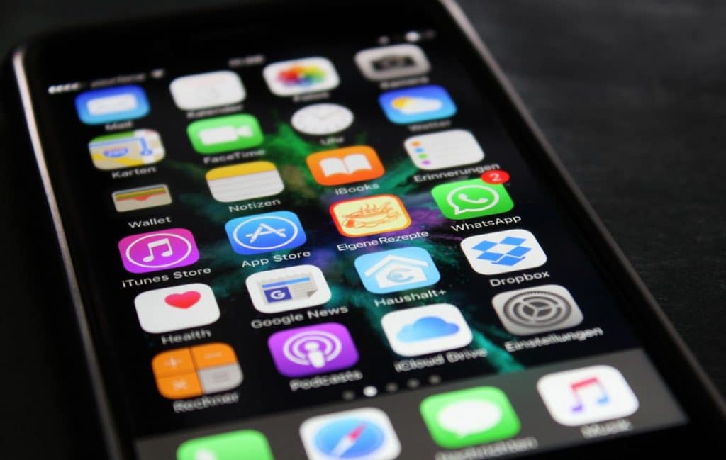 Close-up of a smartphone screen displaying various app icons such as Wallet, iTunes Store, App Store, WhatsApp, Google News, Health, and others. The background is blurred and dark, highlighting the colorful app icons—perfect for discovering iPhone tips and tricks.