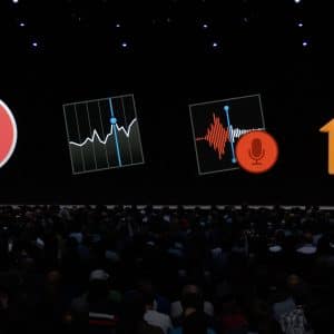 A large audience attends a presentation on a dark stage, with five large app icons displayed on a screen behind the speaker. The icons, optimized for macOS and iOS, include a news icon, a stock market chart, a voice recording app, and a home automation app.