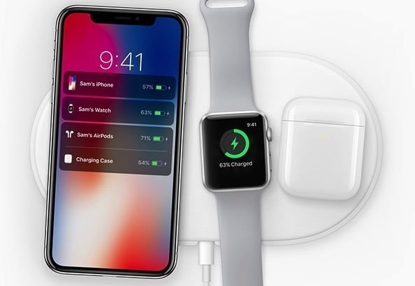 Reports suggest the Apple AirPower is expected imminently. A wireless charging pad charges three Apple devices: an iPhone displaying a battery status screen, an Apple Watch showing a 63% charge, and AirPods in an open charging case. A single charging cable is connected to the pad.