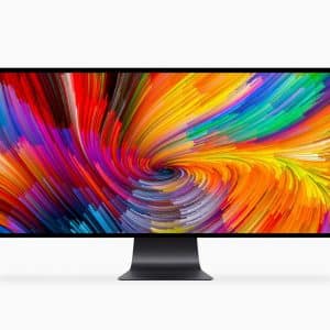 A sleek 6K monitor with a black stand displays a vibrant, colorful abstract swirl pattern. The design features a dynamic mix of red, yellow, orange, blue, and purple hues converging towards the center. The background is plain white—truly headline-worthy tech showcased at WWDC19.