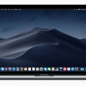 A MacBook Pro laptop displaying a dark-themed desktop with a wallpaper of sand dunes at night. Running macOS 10.15, the desktop contains several folders and icons on the right side of the screen. The dock at the bottom showcases various application icons, including iTunes and other Apple essentials.
