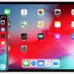 An iPhone and an iPad are shown side by side, both running iOS 13. Their screens display a colorful background with various app icons like Mail, Calendar, Photos, Camera, Contacts, Maps, and Settings. The iPad is in landscape mode for multitasking, while the iPhone is in portrait mode.