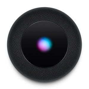 An overhead view of a black cylindrical HomePod with a glowing, multicolored touch control panel on top. The mesh exterior is textured and the light on the panel displays a blend of pink, blue, and green hues. This sleek Apple device offers premium sound quality at an attractive price.