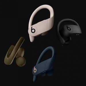 A collection of four wireless earphones from the Beats Brand, in various colors including beige, black, olive green, and navy blue. Each Powerbeats Pro features adjustable ear hooks and the iconic "b" logo. The earphones are set against a sleek black background.