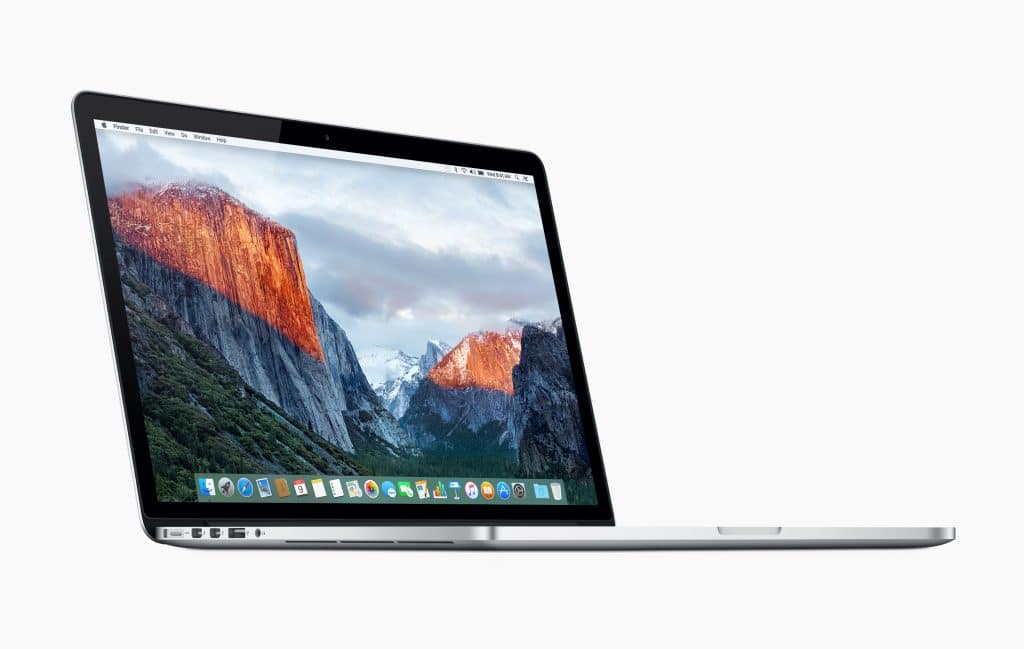 A silver MacBook Pro laptop displaying a mountainous landscape on its screen. The laptop is viewed from a slightly angled side perspective, showing part of the keyboard and trackpad, with several ports visible on the left edge, despite recent battery concerns prompting a recall. The background is white.