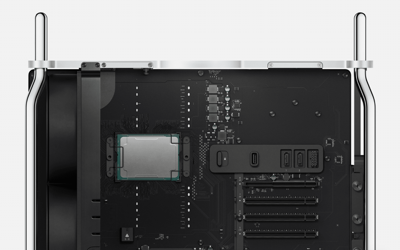 Close-up view of the interior of a high-performance computer tower, reminiscent of the Mac Pro, showcasing the motherboard with a mounted CPU, various connectors, slots for expansion cards, and a cooling mechanism setup. Silver outer frame is visible at the top.