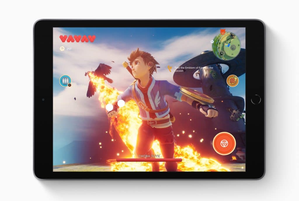 A seventh-generation iPad displays a fantasy action game. The game features a character with spiky hair in an adventurous pose, wielding a flaming sword. Various gaming icons and stats are visible on the larger display, set against a backdrop of a dramatic sky and floating islands.