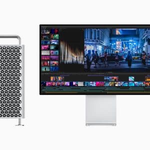 A silver computer tower with a distinctive lattice design stands left of a sleek monitor displaying a video editing interface featuring vibrant cityscape footage. The monitor is supported by a minimalist stand, reminiscent of setups unveiled at the Apple October Event.