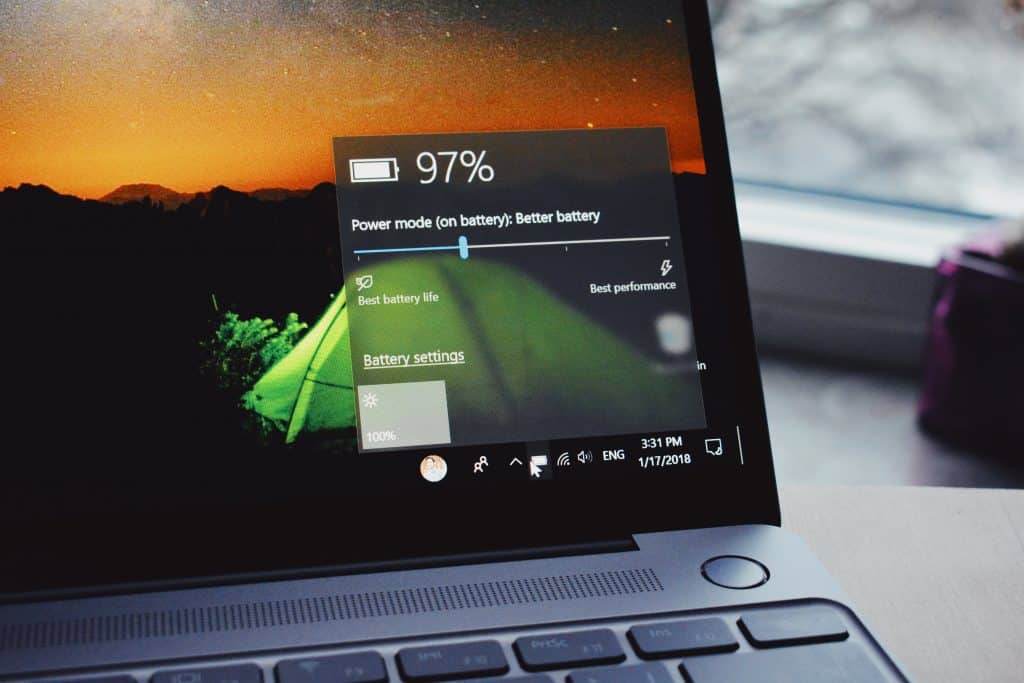 A laptop screen displays the battery status at 97% with the power mode set to "Better battery." The background image on the screen shows a sunset over mountains. The date and time at the bottom right corner indicate 3:31 PM on 1/17/2018. Perfect setup for Windows software developers working on their latest Apple project.