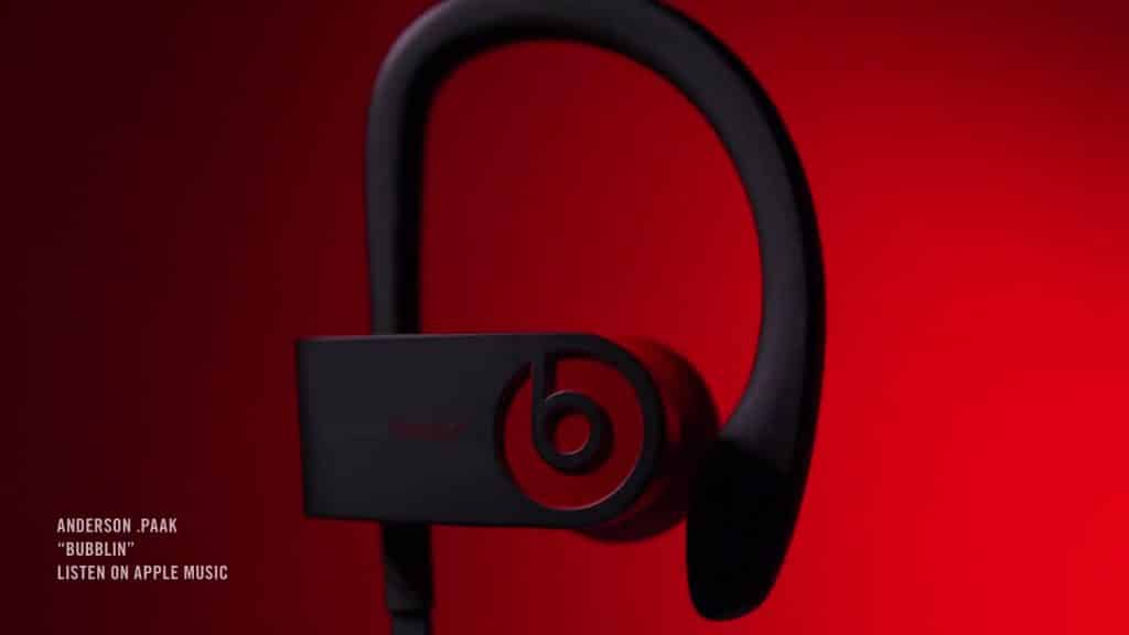 A close-up view of a black Beats by Dre PowerBeats 4 earbud set against a red background. In the lower left corner, text reads: "ANDERSON .PAAK 'BUBBLIN' LISTEN ON APPLE MUSIC." Experience top-tier sound with the latest from early 2020.