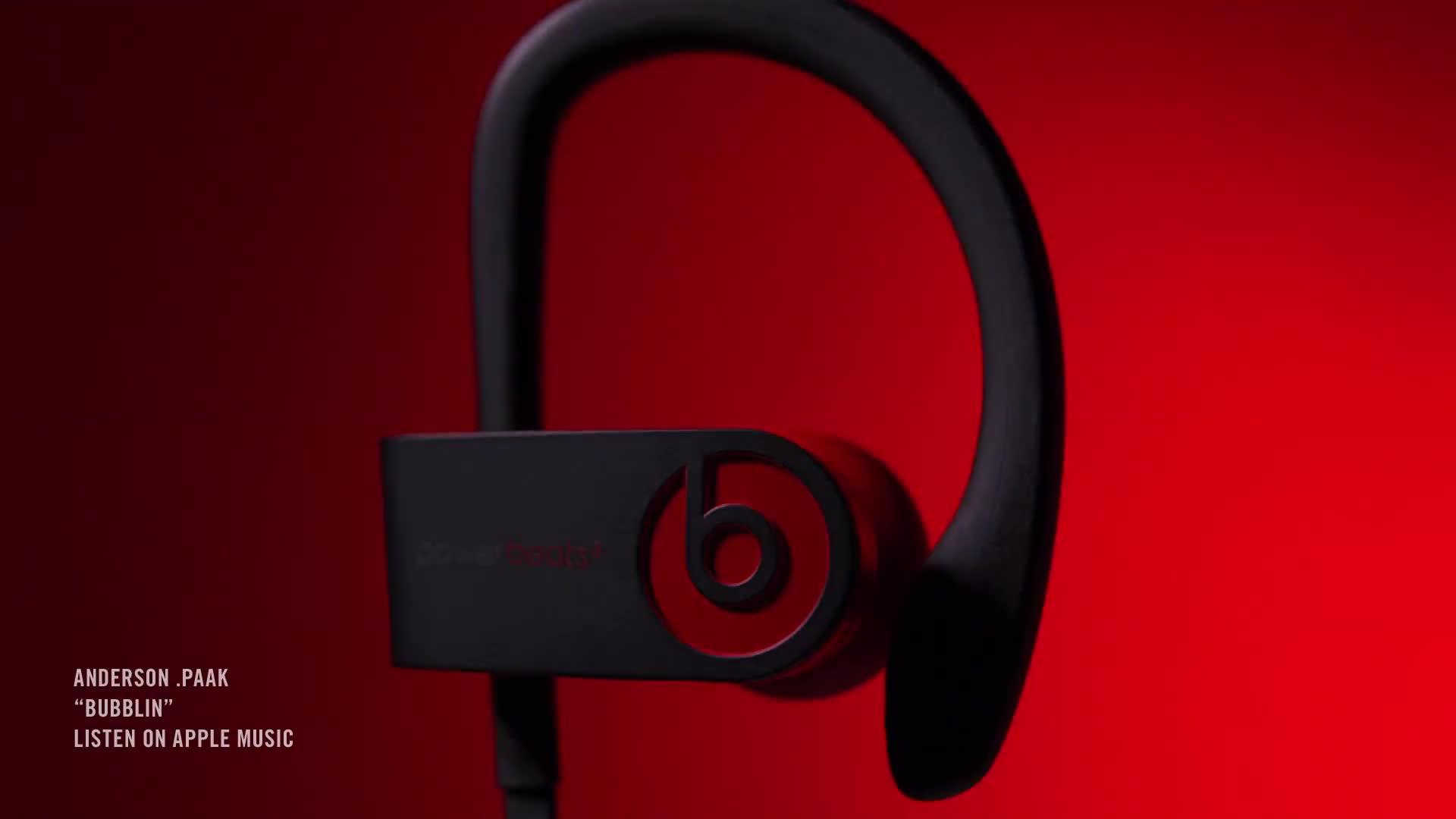 A close-up view of a black Beats by Dre PowerBeats 4 earbud set against a red background. In the lower left corner, text reads: "ANDERSON .PAAK 'BUBBLIN' LISTEN ON APPLE MUSIC." Experience top-tier sound with the latest from early 2020.