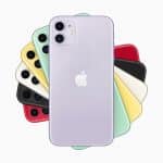 A lavender-colored iPhone 11 is in the foreground, displaying its back with the Apple logo and dual cameras. Behind it, fanned out, are additional iPhone 11 units in black, green, yellow, red, and white colors—all showing their backs and camera setups on a clean white background.