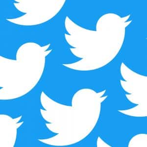 A repeating pattern of white Twitter bird logos on a bright blue background, reminiscent of the icon seen when tweet replies are active.