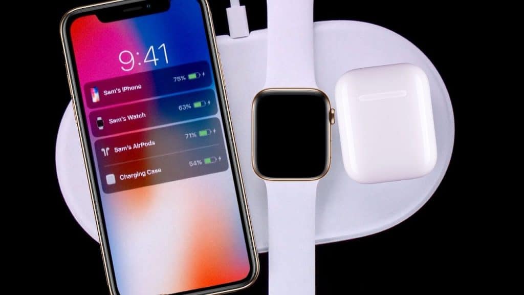 A Mophie wireless charging pad with an iPhone displaying the time 9:41 and battery levels of connected devices on the left. A smartwatch and wireless earbuds case are also placed on the charging pad. All devices are charging, reminiscent of Apple's ambitious AirPower launch.