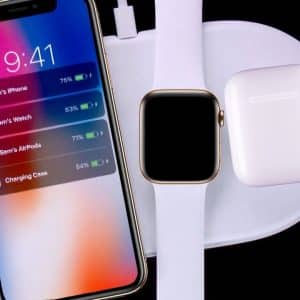 A Mophie wireless charging pad with an iPhone displaying the time 9:41 and battery levels of connected devices on the left. A smartwatch and wireless earbuds case are also placed on the charging pad. All devices are charging, reminiscent of Apple's ambitious AirPower launch.