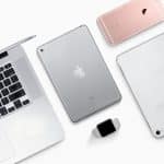 A flat lay image of several Apple devices running iOS and macOS displayed on a white surface, including a MacBook, an iPad, an Apple Watch, a rose gold iPhone, and a silver iPhone. These devices exemplify the seamless integration of Universal Purchases across the Apple ecosystem.