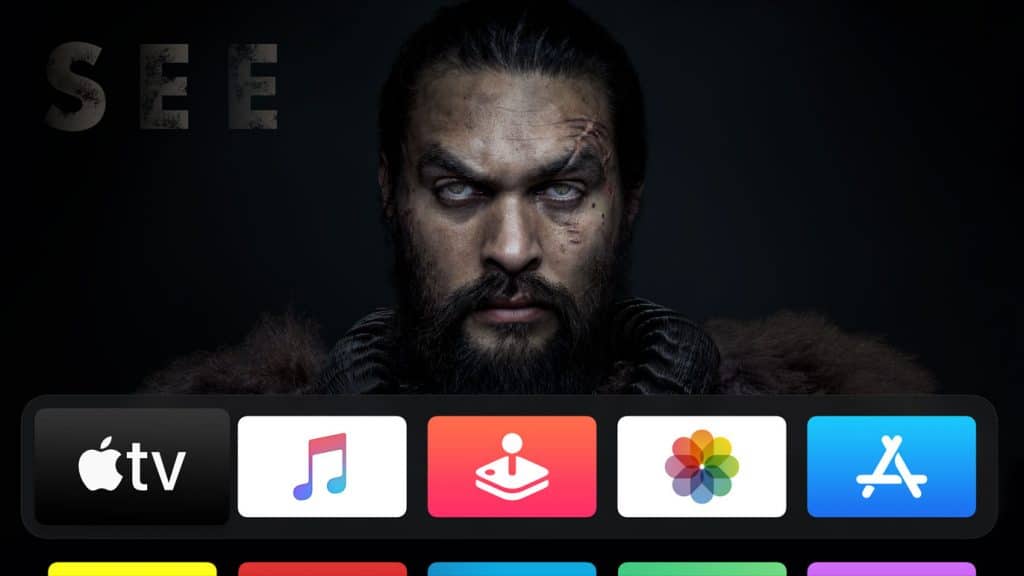 A promotional image for the series "See" featuring a stern-looking man with white eyes, facial scars, and a dark background. Below him is a user interface with icons for Apple TV, Music, Arcade, Photos, and App Store from Apple.