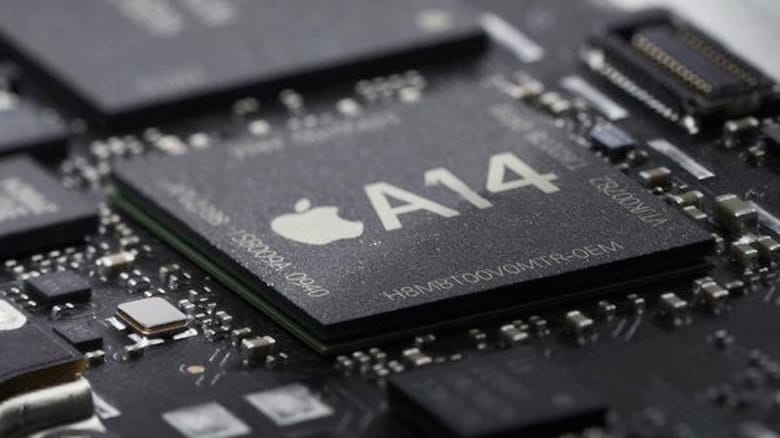 Close-up image of an A14 Bionic chip on a circuit board, displaying the Apple logo and the label "A14." The chip is surrounded by other electronic components, highlighting the intricate details of the board's layout.