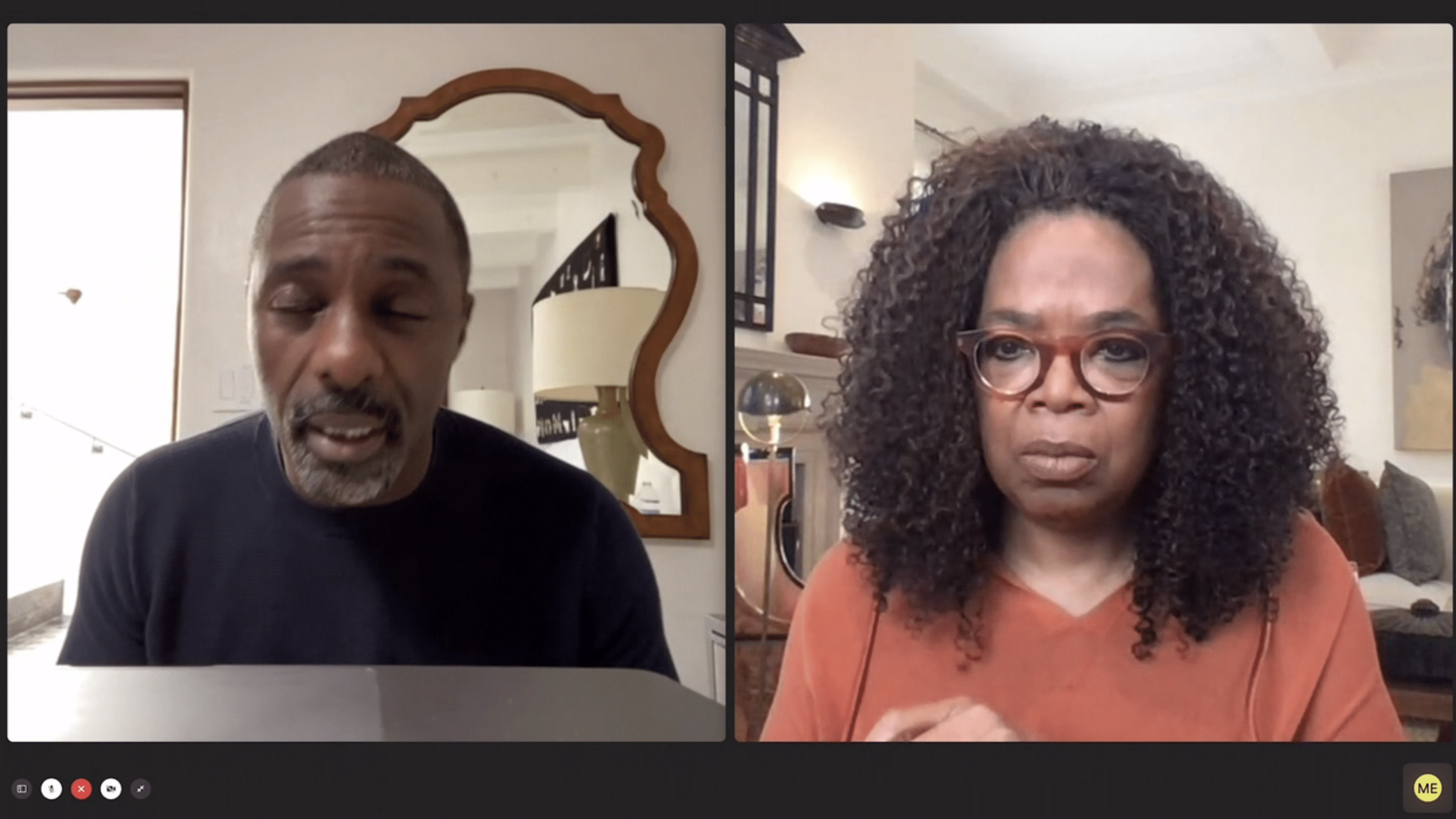 A video call screenshot showing a man on the left and a woman on the right, both appearing to be in a serious discussion about COVID-19. The man has short hair and wears a dark top, while the woman, who looks like she could host an Apple TV+ show with Oprah, has curly hair, glasses, and an orange top. Both are in their respective homes.