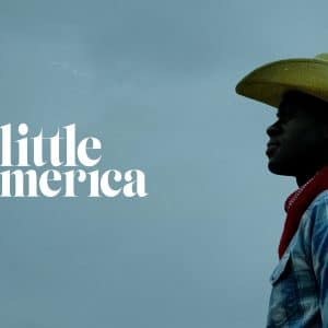 A person in profile wearing a cowboy hat and a plaid shirt stands against a dark, cloudy sky. The words "Little America" are displayed in large white letters on the left side of the image, hinting at an anticipated content premiere. The person appears to be looking into the distance.