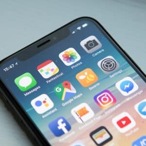 A smartphone displaying its home screen with various app icons including Messages, Fantastical, Photos, Camera, Assistant, Google Maps, Messenger (featuring the new Facebook Messenger redesign), Instagram, and Settings. The time shown is 15:47. The phone is placed on a light-colored surface.