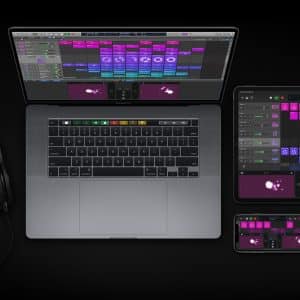 A laptop, tablet, and smartphone display music production software with similar colorful interfaces. The central laptop, running Logic Pro X after a recent software update, is flanked by the tablet and smartphone. A pair of Apple headphones is plugged into the laptop. All devices rest on a dark surface.