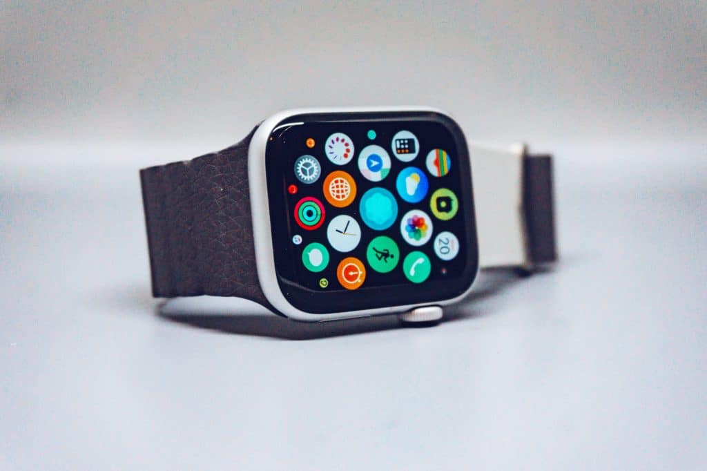 A number one smartwatch with a rectangular face and dark strap is displayed on a smooth surface, reminiscent of the popular Q1 2020 models. Its screen showcases various colorful app icons arranged in a grid, much like the Apple Watch.