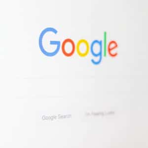 A screenshot of the Google homepage, displaying the colorful Google logo above the search bar. Below the search bar are two buttons labeled "Google Search" and "I'm Feeling Lucky." The background is plain white, with subtle hints of Google Content Highlighting in action.