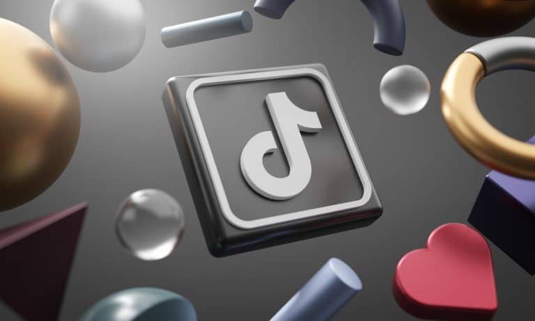 A 3D-rendered TikTok logo is surrounded by various geometric shapes, including spheres, cylinders, and a heart, on a dark background. The metallic and translucent shapes create a dynamic scene that could attract influencers from any TikTok rival platform.