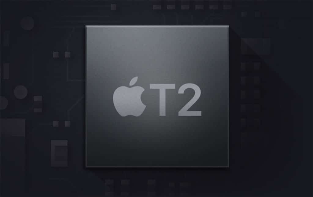 Dark-themed close-up image of an Apple T2 security chip with the Apple logo and "T2" prominently featured on its surface. The background resembles a circuit board, adding a tech-centric context to the image.