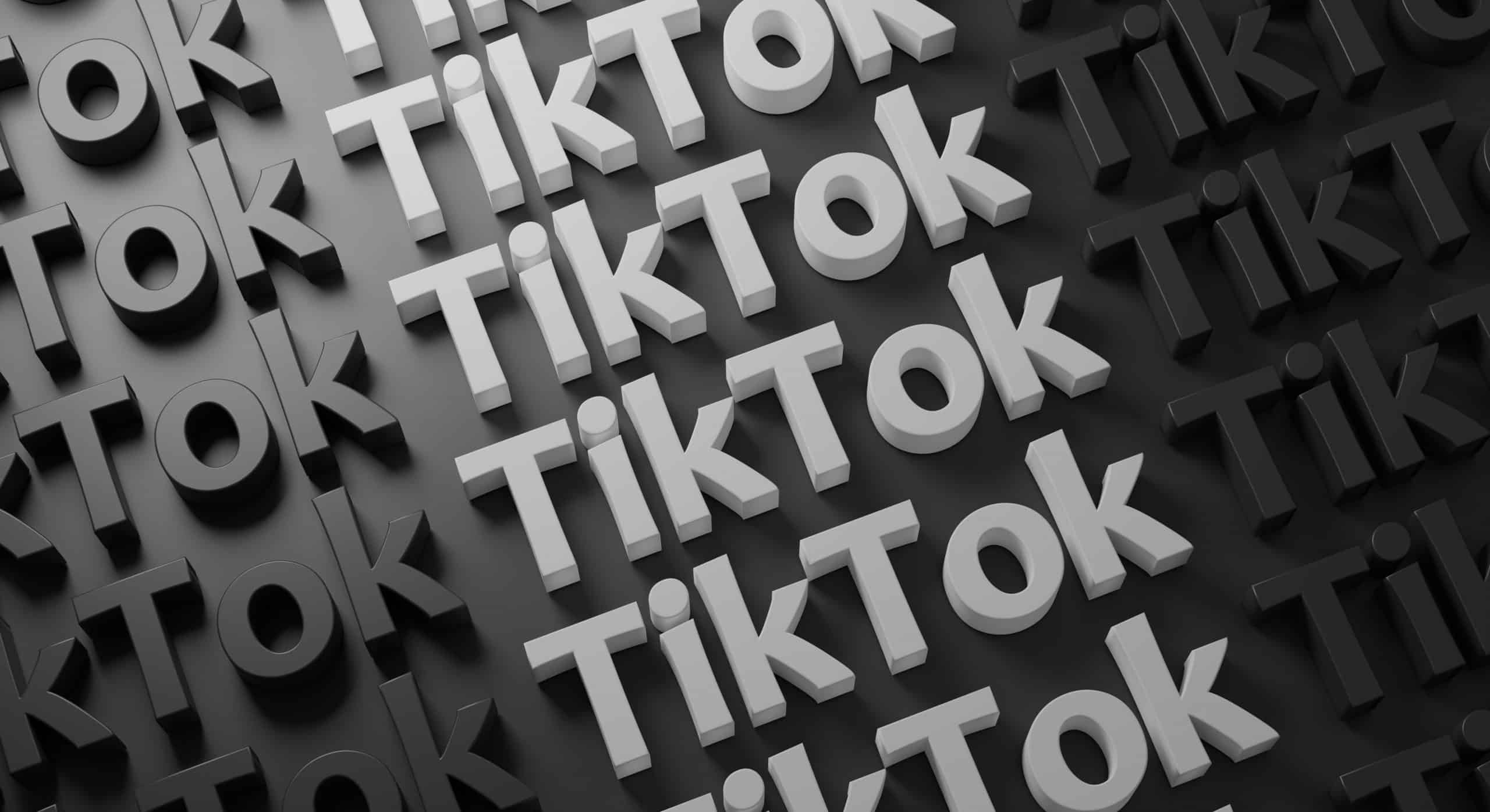 A 3D black and white pattern features multiple repetitions of the "TikTok" logo arranged in diagonal lines, crafting a visually engaging, staggered effect. Reminiscent of global business branding strategies seen in Microsoft designs, the background alternates between light and dark shades for added depth and contrast.