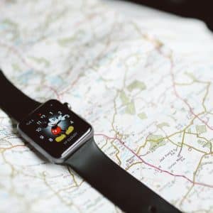 A smartwatch with a Mickey Mouse watch face displaying the time is placed on a detailed paper map. The watch has a black band, and the map features roads, landmarks, and various geographic details of Ireland.