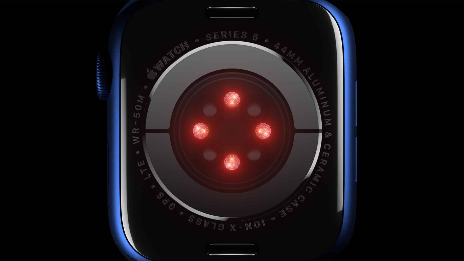 Close-up of the back of an Apple Watch Series 6, showcasing its health sensors emitting red light. The watch case is labeled "44mm Aluminum & Ceramic Case," "ION-X Glass," and "GPS LTE WR 50M." The watch is blue with a dark background, amidst discussions of a recent patent dispute.