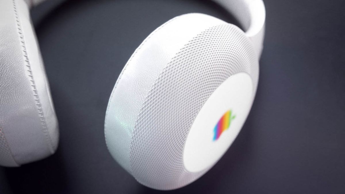 Close-up of a white over-ear headphone with a retro rainbow Apple logo on the side. The earcup has a textured surface, and the background is a solid dark color. Expected this Fall, these headphones blend seamlessly with other Apple devices.