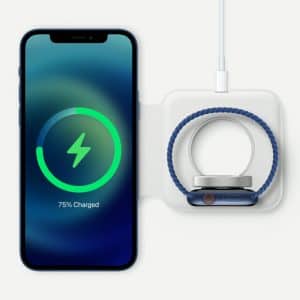 An iPhone 12 mini and a smartwatch are shown side by side on a wireless charging pad. The smartphone's screen displays a 75% charge completion with a green charging symbol. The smartwatch, attached to the charger, has a blue band and is positioned next to the $699 phone.