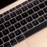 MacBook 12 Inch - Close-up of a gold MacBook keyboard with black backlit keys, showing the QWERTY layout and function keys.
