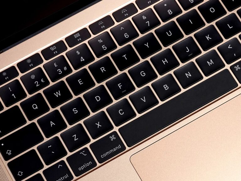 MacBook 12 Inch - Close-up of a gold MacBook keyboard with black backlit keys, showing the QWERTY layout and function keys.