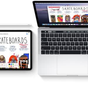 A top-view image shows a Mac and an iPad next to each other on a white surface. Both screens display similar colorful skateboard-themed web pages with vibrant graphics and text, showcasing the seamless integration of Apple's Ecosystem. A stylus lies on top of the closed keyboard cover beside the iPad.